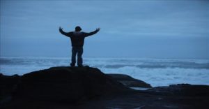 man rock staring sea